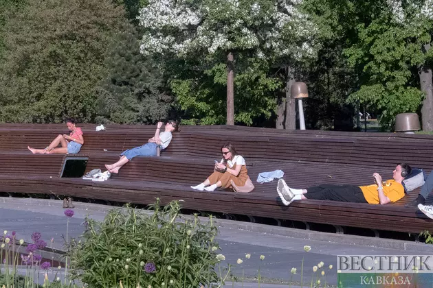 Отдыхающиет на скамейке в парке в жаркую погоду