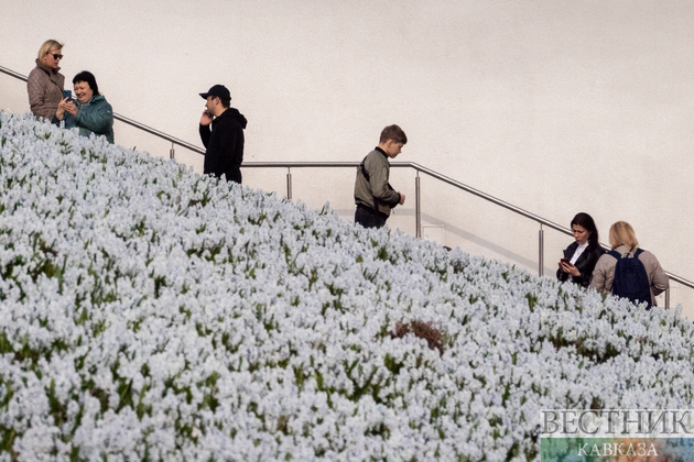 Посетители парка Зарядье в Москве у поляны с цветами