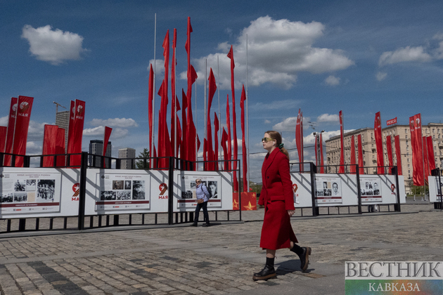 Девушка на фоне  праздничных флагов и выставки ко Дню Победы в парке Победы