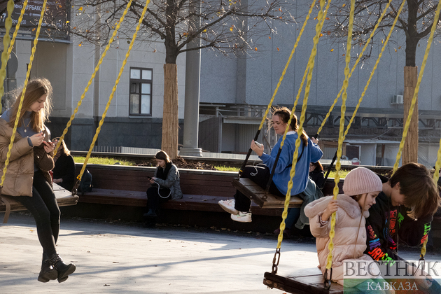 Девушки и дети качаются на качелях на Триумфальной площади в Москве