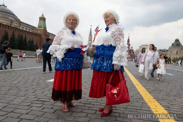 Туристы в костюмах в цветах российского флага на Красной площади