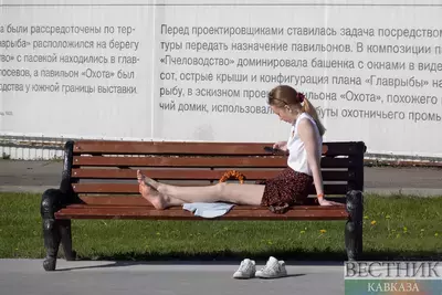 Девушка отдыхает на скамейке в парке в жаркую погоду