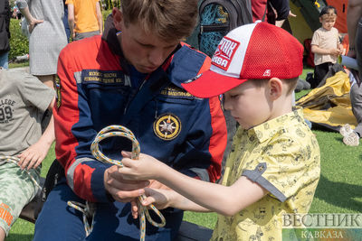 Спасатель учит ребенка завязывать узел